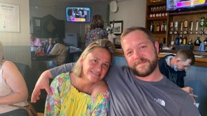 Julia stood next to her brother Dava, his arm round her shoulders and they're both smiling.